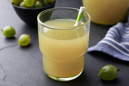 Tasty gooseberry juice in glass on black tableの写真素材