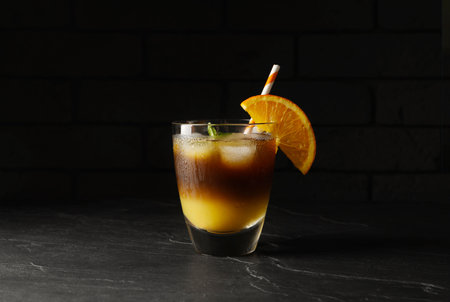 Tasty refreshing drink with coffee and orange juice on gray table against dark backgroundの写真素材