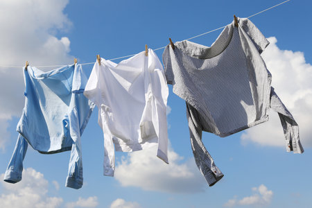 Clean clothes hanging on washing line against sky. Drying clothesの写真素材