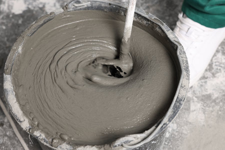 Worker mixing concrete in bucket indoors, closeupの写真素材