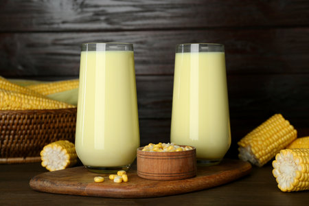 Tasty fresh corn milk in glasses and cobs on wooden tableの写真素材