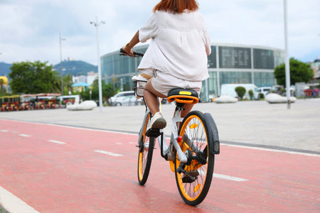 Young woman riding bicycle on lane in city, back view