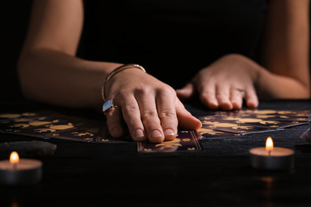 Soothsayer predicting the future with tarot cards at table in darkness, closeupの写真素材