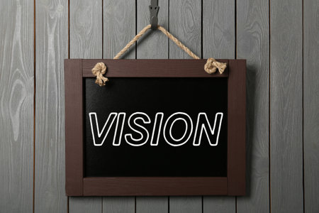 Small chalkboard with word Vision hanging on gray wooden wall
