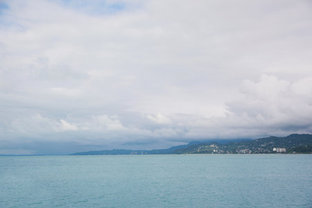 Picturesque view of sea with coastline and mountains under cloudy sky
