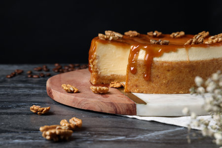 Sliced delicious cheesecake with caramel and walnuts on black marble table, space for textの写真素材