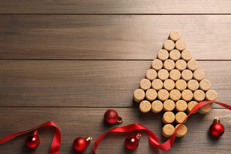 Christmas tree made of wine corks, red ribbon and baubles on wooden table, flat lay. Space for textの写真素材