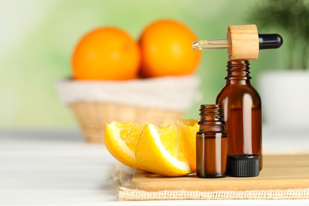 Bottles of essential oil, pipette and orange on white wooden table, space for textの写真素材