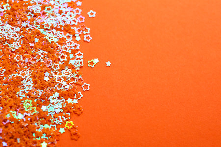 Shiny bright star shaped glitter on orange background. Space for textの写真素材