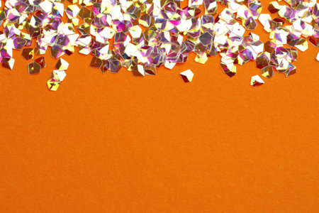 Pile of shiny glitter on orange background, flat lay. Space for textの写真素材