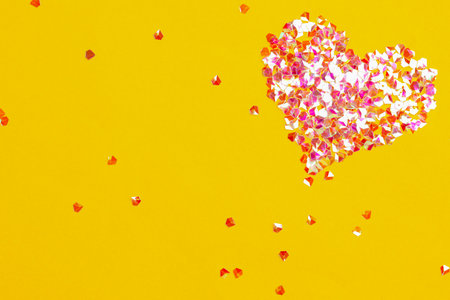 Heart made with shiny glitter on yellow background, flat layの写真素材