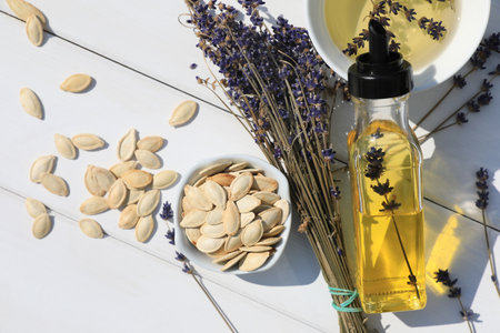 Healthy cooking oil, lavender flowers and pumpkin seeds on white wooden table, closeupの写真素材