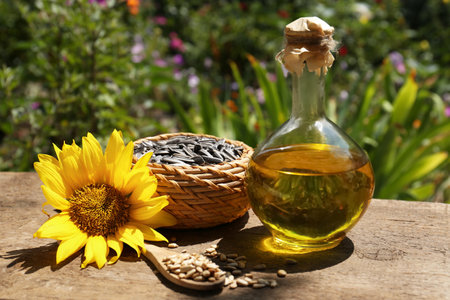 Bottle of sunflower oil, seeds and flower on wooden table outdoorsの写真素材