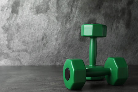 Green vinyl dumbbells on table against gray background. Space for textの写真素材