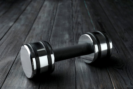 One metal dumbbell on black wooden tableの写真素材