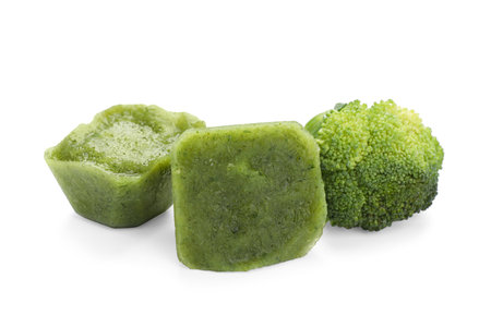 Frozen broccoli puree cubes and fresh broccoli isolated on whiteの写真素材