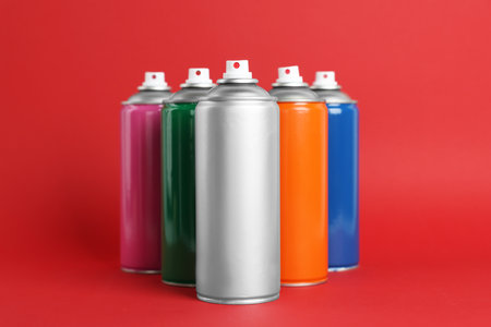 Colorful cans of spray paints on red backgroundの写真素材