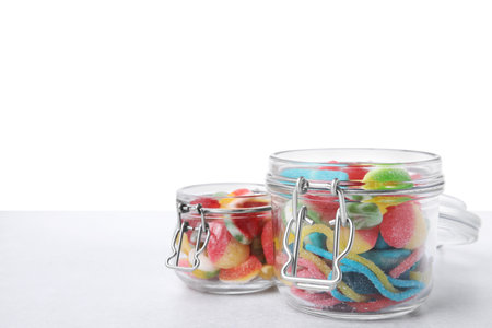 Tasty jelly candies in jars on light gray tableの写真素材