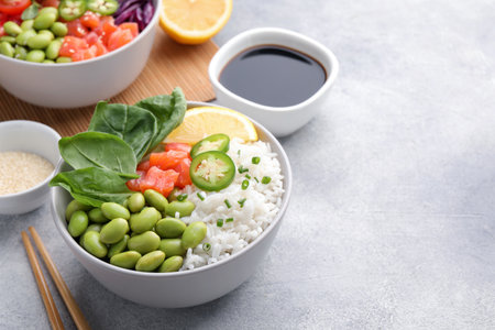 Poke bowl with salmon, edamame beans and rice on light gray table, space for textの写真素材