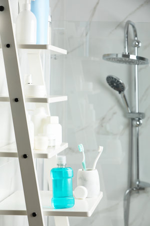 Bottle of mouthwash, toothbrushes and dental floss on white shelf in bathroomの写真素材