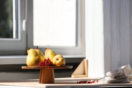 Stand with juicy pears, red currants and double-sided backdrop on table in photo studio. Space for textの写真素材