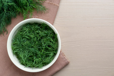 Bowl of fresh dill on wooden table, top view. Space for textの写真素材