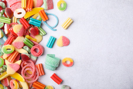 Many tasty colorful jelly candies on white table, flat lay. Space for textの写真素材