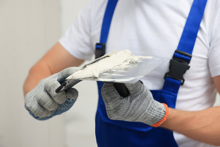 Worker with putty knives and plaster near wall, closeupの写真素材