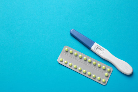 Birth control pills and pregnancy test on light blue background, top view. Space for textの写真素材