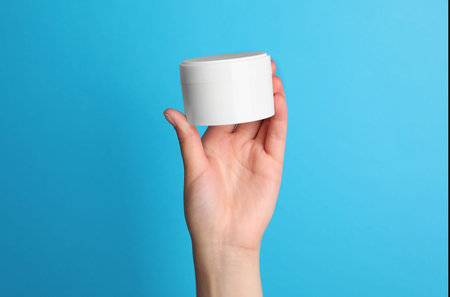 Woman holding jar of face cream on light blue background, closeupの写真素材