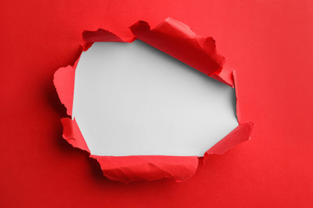 Hole in red paper on white backgroundの写真素材