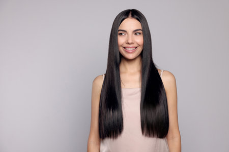 Portrait of beautiful young woman with healthy strong hair on light gray background, space for textの写真素材