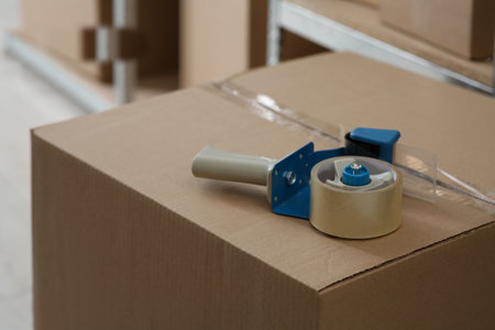 Adhesive tape dispenser on cardboard box indoors