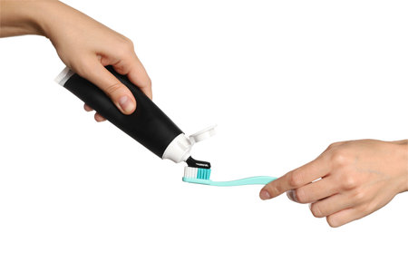 Woman applying charcoal toothpaste on brush against white background, closeup