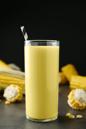 Freshly made corn juice in glass on gray table against black backgroundの写真素材
