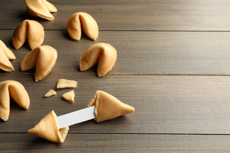 Tasty fortune cookies with predictions on wooden table, space for textの写真素材