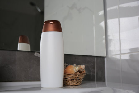 Bottle of shower gel and wicker basket with shells on sink in bathroom. Space for textの写真素材