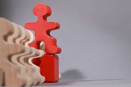 Red figure among wooden ones on light gray background, closeup with space for text. Recruiter searching employeeの写真素材