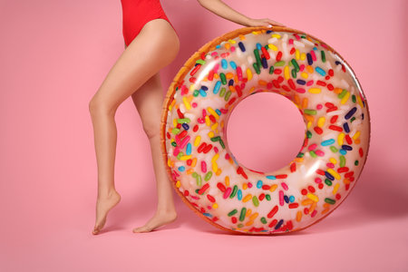 Young woman with inflatable ring against pink background, closeupの写真素材
