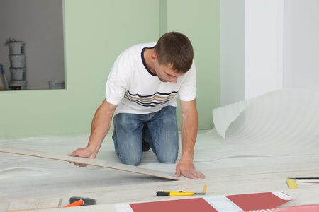 Man installing new laminate flooring in roomの写真素材
