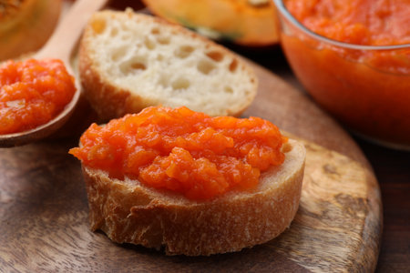 Slices of bread with delicious pumpkin jam and fresh pumpkin on wooden table, closeupの写真素材