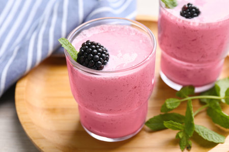 Delicious blackberry smoothie in glasses on wooden tray, closeupの写真素材