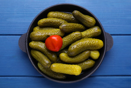 Serving pan with pickled cucumbers and peppers on blue wooden table, top viewの写真素材