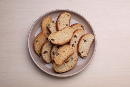 Plate of sweet hard chuck crackers with raisins on wooden table, top viewの写真素材