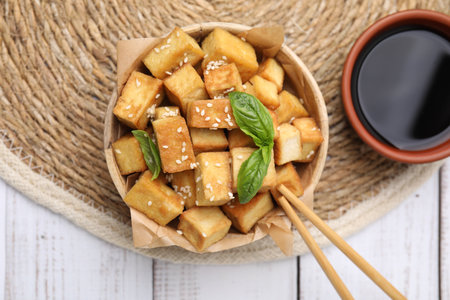 Delicious fried tofu with basil and sesame seeds served on white wooden table, flat layの写真素材