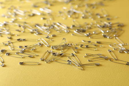 Many new safety pins on yellow backgroundの写真素材