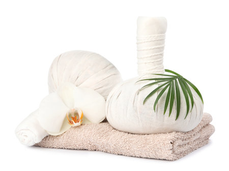 Herbal massage bags, flower, green leaf and towel on white background. Spa supplyの写真素材