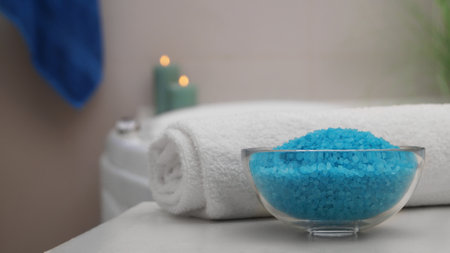 Bowl with bath salt and fluffy towel on table in bathroom. Space for textの写真素材
