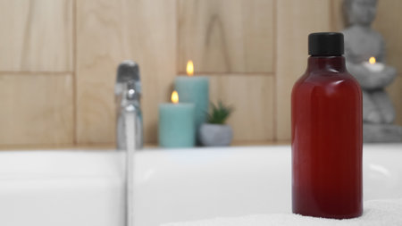 Red bottle of bubble bath on tub indoors, space for textの写真素材