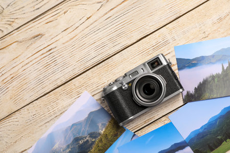 Vintage photo camera and beautiful printed pictures on wooden table, flat lay with space for text....
